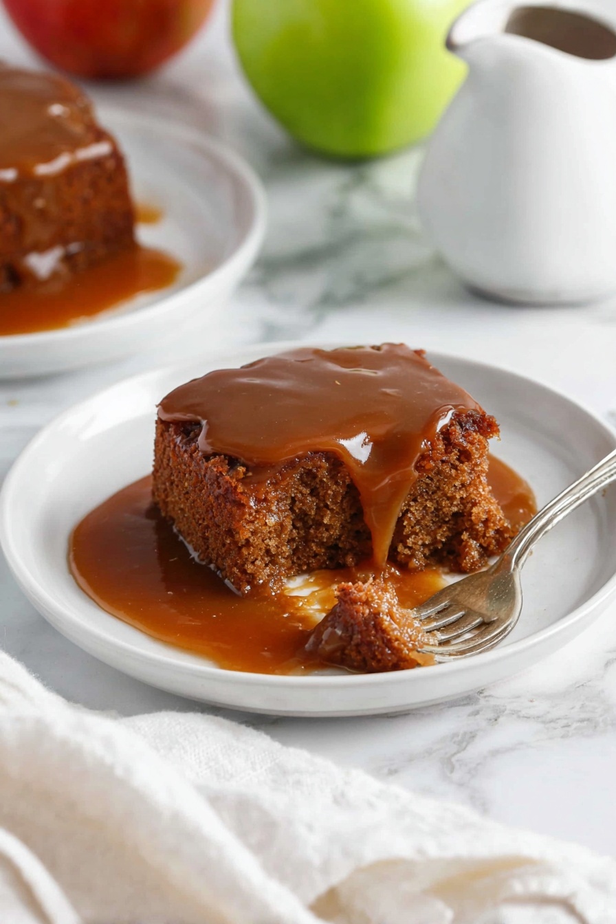 A white round plate holds a piece of brown cake with a moist, crumbly texture, covered with a shiny, thick caramel sauce flowing slightly over the edges. A silver fork is breaking a small bite from the cake, showing a soft, dense inside soaked with the caramel sauce. The plate sits on a white marbled surface with a green apple and a white pitcher visible nearby. Another plate with a similar cake piece and caramel sauce is partially seen in the background. A white cloth is casually placed near the front edge of the frame. Photo taken with an iphone --ar 2:3 --v 7