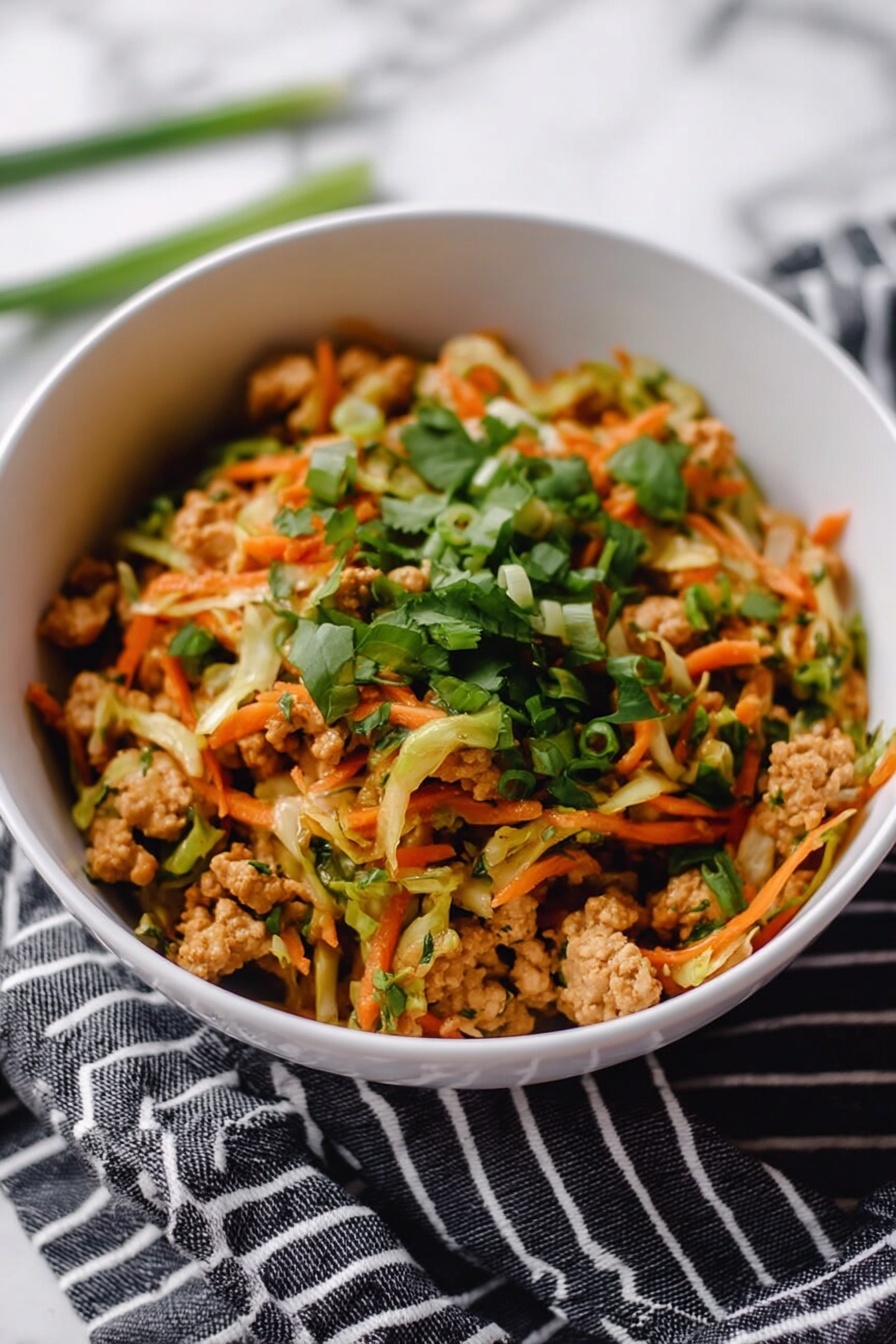 A white bowl filled with a colorful mix of shredded light green cabbage and small pieces of cooked light brown chicken, topped with bright green chopped herbs and slices of green onion. There are drops and streaks of red sauce on top, adding contrast. Two medium brown wooden chopsticks rest crossed on the bowl’s edge. The bowl is placed on a white marbled surface with a blurred white bowl of more of the same dish in the background. Photo taken with an iphone --ar 2:3 --v 7